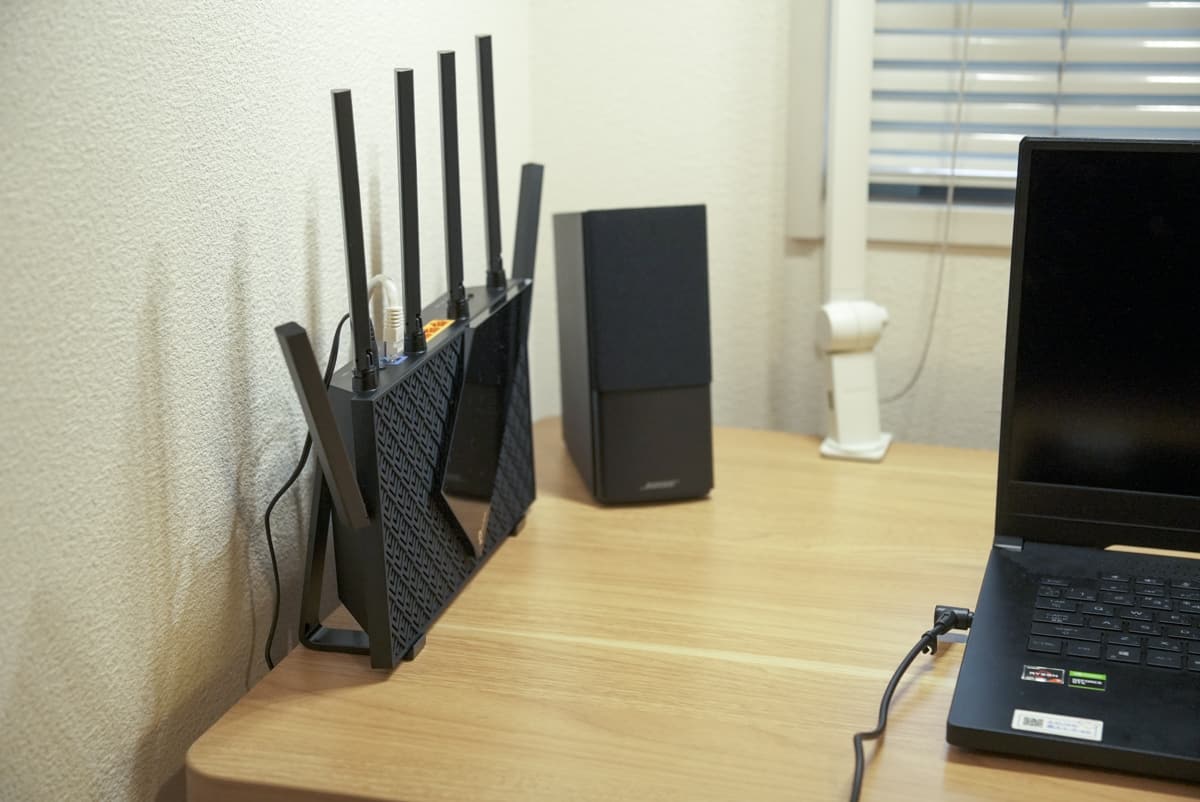 TP-Link Archer AX73 を縦置きでデスクの隅に設置している様子の画像